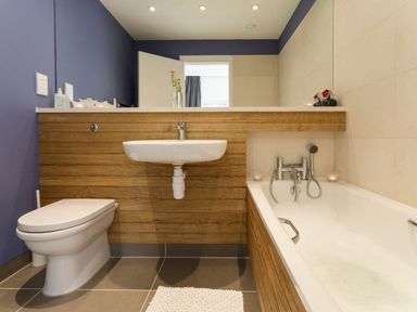 A bathroom with a bathtub filled with water a toilet and a wall-mounted sink at The Gallery in Aveton Gifford