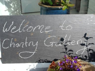 A chalkboard sign with welcome message and potted plants with purple flowers and green leaves