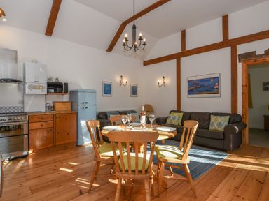 A kitchen and dining area with wooden chairs and table a blue refrigerator and brown sofas at Bradbridge Barn in Newton Ferrers