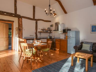 A kitchen and dining area with wooden table and chairs a blue fridge and a brown sofa at Bradbridge Barn in Newton Ferrers