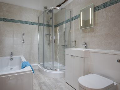 A bathroom with a bathtub a glass shower enclosure a sink with a cabinet and a toilet at Bradbridge Barn in Newton Ferrers
