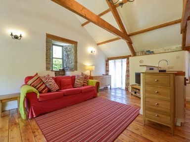 A living room with a red sofa and striped rug at Parsonage Farm Cottage in Newton Ferrers