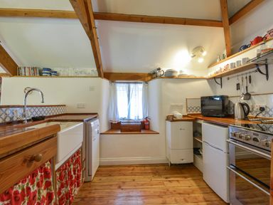 A kitchen with wooden countertops a sink a window and various kitchen appliances at Parsonage Farm Cottage Newton Ferrers