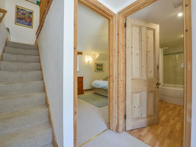 Carpeted staircase next to doorways leading to a bedroom and a bathroom at Parsonage Farm Cottage in Newton Ferrers