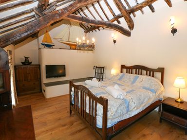A bedroom with wooden beams bed with linens wooden furniture and model sailboats at Garth Morthin The Farmhouse in Porthmadog