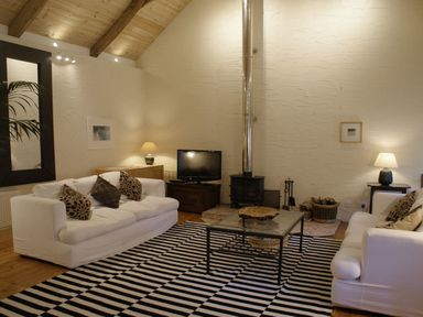 A living room with two white sofas and a striped rug at The Barn in Aveton Gifford