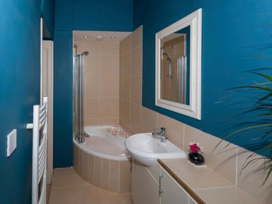 A bathroom with a corner bathtub a sink wall mirror and candles at The Music Room in Aveton Gifford