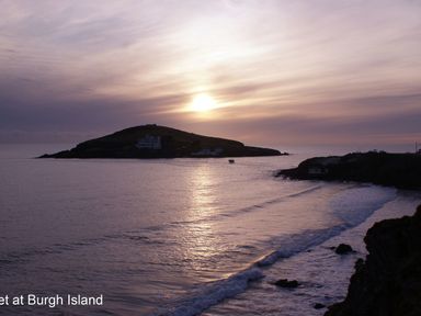 A sunset over the sea with an island and waves at 3 Tarifa in Bigbury-on-Sea