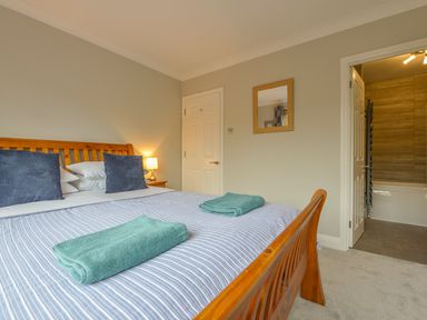 A bedroom with a wooden bed and blue striped bedding with two folded towels on the bed at 3 Tarifa in Bigbury-on-Sea