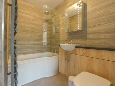 A bathroom with a corner bathtub a sink with cabinet a mirrored cabinet and a towel radiator at 3 Tarifa in Bigbury-on-Sea