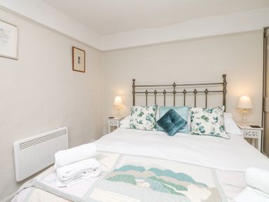 A bedroom with a metal bed frame cushions and bedside tables with lamps at The Bathing House in Ashprington