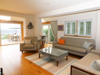 A living room with sofas a coffee table and a view of an outdoor dining area at Dove Cottage in Dittisham
