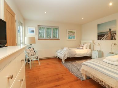 A bedroom with two beds striped blankets wooden floor and nautical themed pictures at Dove Cottage in Dittisham
