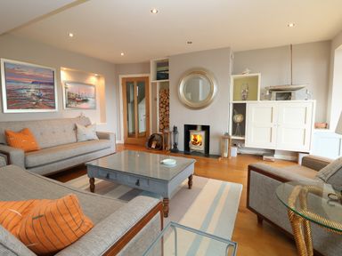 A living room with a fireplace two gray sofas a wooden coffee table and paintings on the wall at Dove Cottage in Dittisham