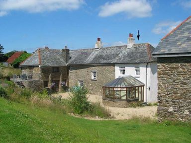 A stone house with a glass conservatory and a grassy yard at Oak Tree in Halwell