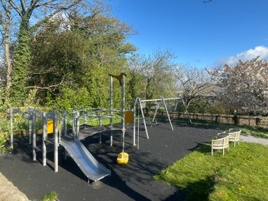 A playground with a slide and swings at Oak Tree in Halwell