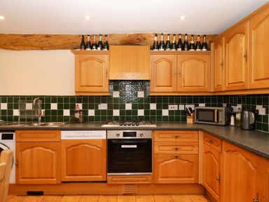 A kitchen with wooden cabinets and appliances at Oak Tree in Halwell
