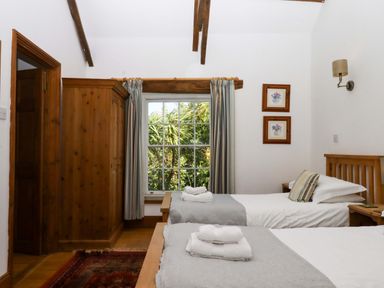 A bedroom with two beds and a wardrobe at Oak Tree in Halwell