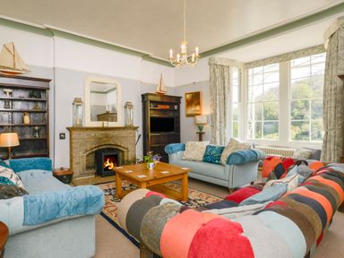 A living room with a fireplace three sofas a wooden coffee table and large windows at Woodlands in Dartmouth