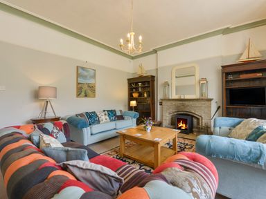 A living room with sofas a wooden coffee table a fireplace and bookshelves at Woodlands in Dartmouth