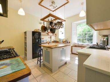 A kitchen with a central island and hanging pots above it at Woodlands in Dartmouth