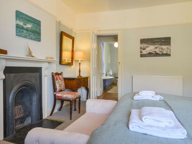 A bedroom with a fireplace a chair a wooden desk a mirror and a view into a bathroom at Woodlands in Dartmouth