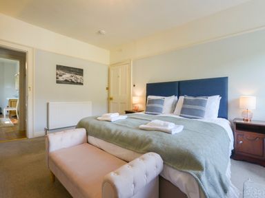 A bedroom with a double bed two pillows two lamps a wooden nightstand and a pink bench at Woodlands in Dartmouth