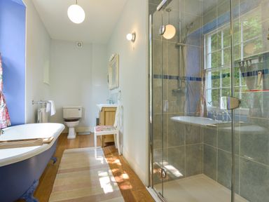 A bathroom with a clawfoot bathtub shower enclosure toilet sink and a chair at Woodlands in Dartmouth