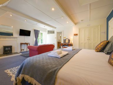 A bedroom with bed towels a red sofa a television and a dressing table at Woodlands in Dartmouth