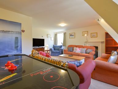 A living room with sofas a coffee table a television and an air hockey table at Woodlands in Dartmouth