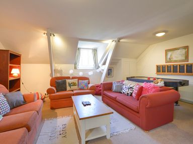 A sitting room with red sofas a white coffee table an air hockey table and shelving at Woodlands in Dartmouth