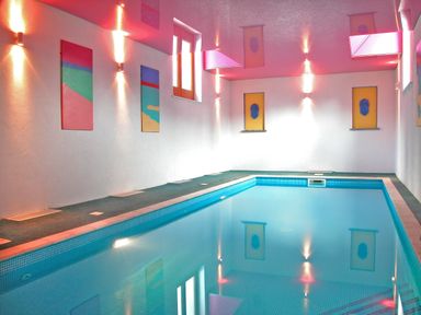 An indoor swimming pool with tiled walls and decorative wall art at Fixit Cottage in Kingsbridge