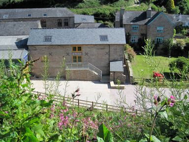 A stone building with stairs and flowers in the foreground at Fixit Cottage in Kingsbridge