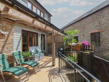 An outdoor patio with seating and planters at Fixit Cottage in Kingsbridge