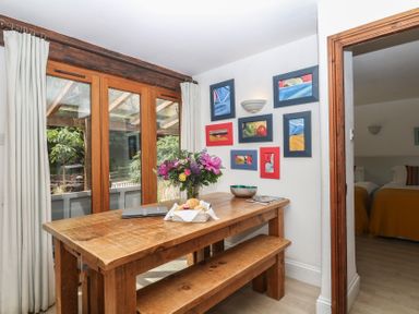 A dining room with a wooden table and flower vase at Fixit Cottage in Kingsbridge