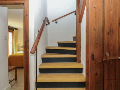 A staircase with handrail leading to an upper floor at Fixit Cottage in Kingsbridge
