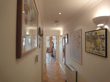 A hallway with tiled floor and framed maps and pictures on the walls at 5 Burgh Island Causeway in Bigbury-on-Sea
