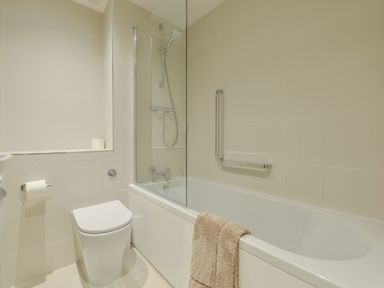 A bathroom with a toilet a bathtub with a showerhead a glass shower screen and a towel hanging on the bathtub at 5 Burgh Island Causeway in Bigbury-on-Sea