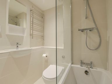 A bathroom with a sink a toilet a bathtub with a shower and a towel radiator at 5 Burgh Island Causeway in Bigbury-on-Sea