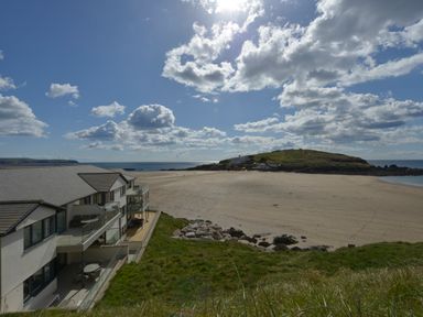 A beach with a building on the side and a hill in the background at 5 Burgh Island Causeway in Bigbury-on-Sea