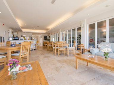 A dining area with wooden tables and chairs and a counter at 13 Burgh Island Causeway in Bigbury-on-Sea