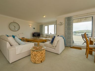 A living room with white sofas a wooden coffee table and a round cork side table with a glass top at 13 Burgh Island Causeway in Bigbury-on-Sea