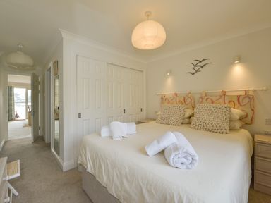 A bedroom with a double bed with folded towels on it two bedside tables and a closet with sliding doors at 13 Burgh Island Causeway in Bigbury-on-Sea