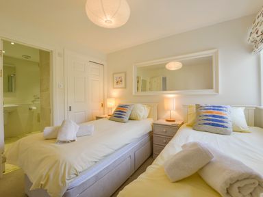 A bedroom with two single beds bedside tables and a large mirror at 13 Burgh Island Causeway in Bigbury-on-Sea