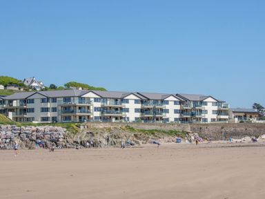 A beachfront apartment complex with balconies by a sandy beach at 13 Burgh Island Causeway in Bigbury-on-Sea