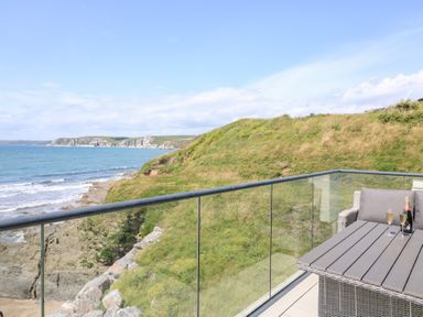 A balcony with a table and chairs overlooking the ocean at 27 Burgh Island Causeway Bigbury-on-Sea