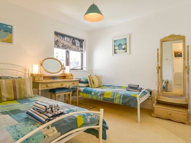 A bedroom with two single beds a wooden dressing table with mirror and a standing mirror at 24 Burgh Island Causeway in Bigbury-on-Sea