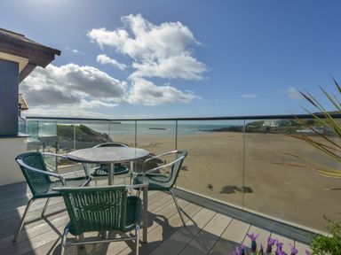 A balcony with a round table and four chairs overlooking a sandy beach and sea at 23 Burgh Island Causeway in Bigbury-on-Sea