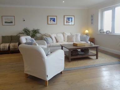 A living room with white armchairs a sofa and a coffee table with baskets at 23 Burgh Island Causeway in Bigbury-on-Sea