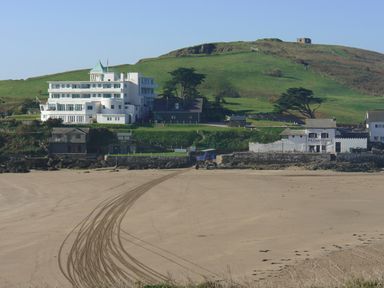 A building near a beach with tire tracks on sand and green hills in the background at 23 Burgh Island Causeway in Bigbury-on-Sea